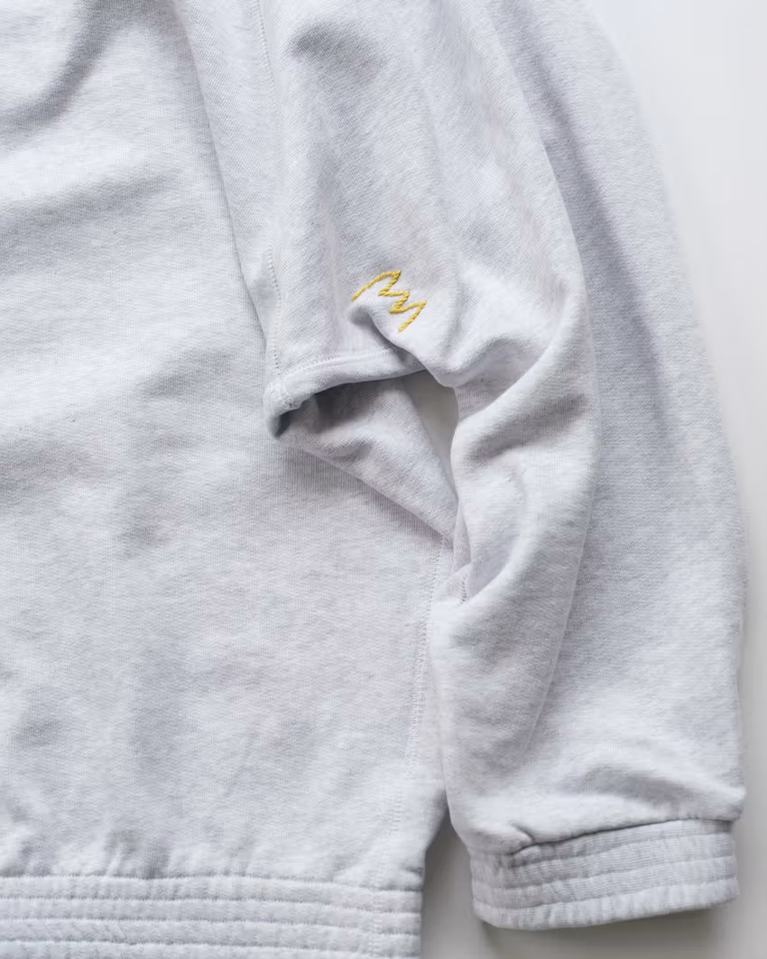 Small embroidery sits near the junction of sleeve and body