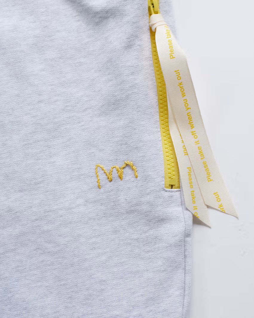 A yellow ribbon and small embroidery echo the top’s details