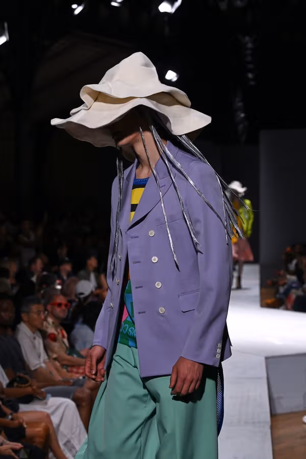 垂れる帯付きの白い二重つば帽と紫のジャケット