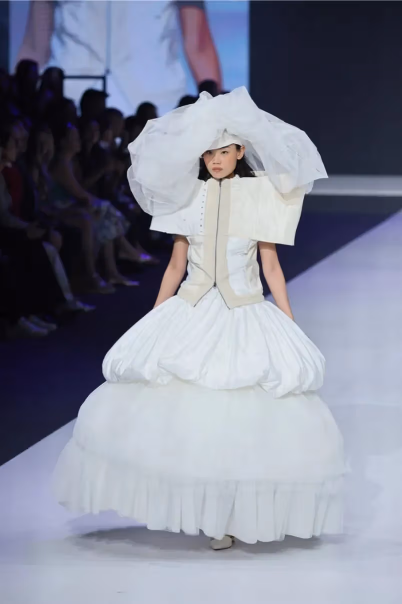 นางแบบแสดงชุดสีขาวและเครื่องประดับศีรษะขนาดใหญ่