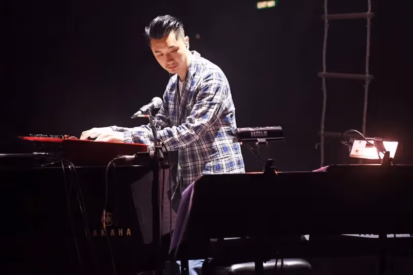黒いピアノの前に座って演奏するEdward Chan