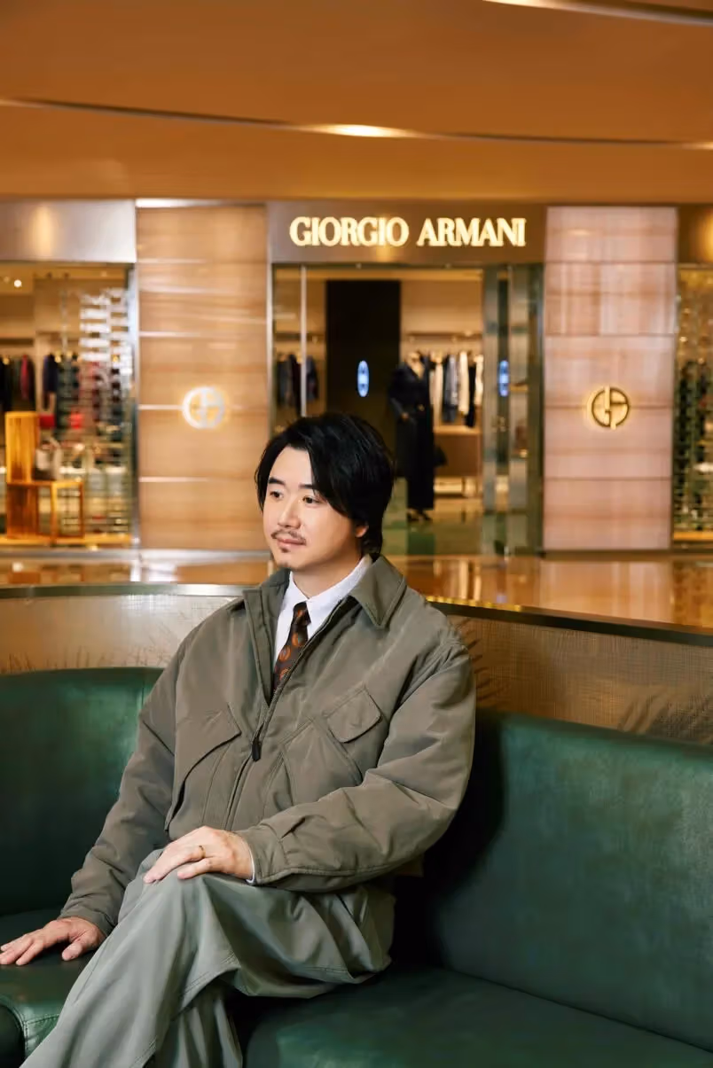 ブランド展示空間でグレーグリーンの服を着て座るEdward Chan