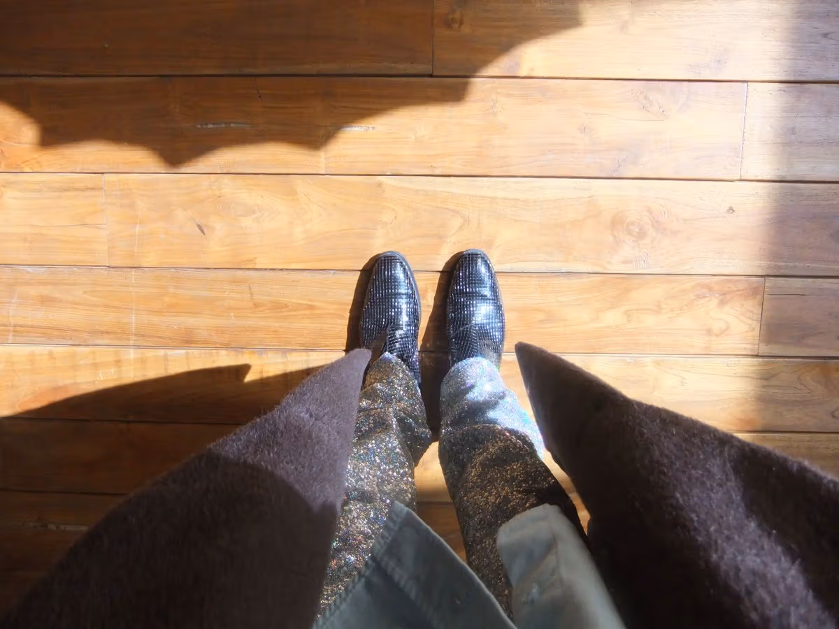 Black Belmont zip boots and the wooden floor show different reflective textures.
