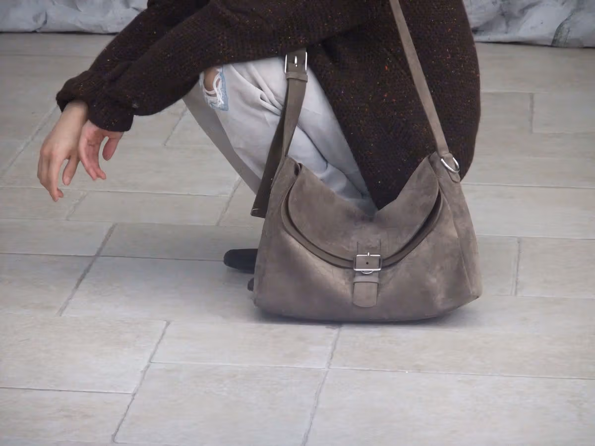 A gray suede Double Up Large bag shown in relation to the body.