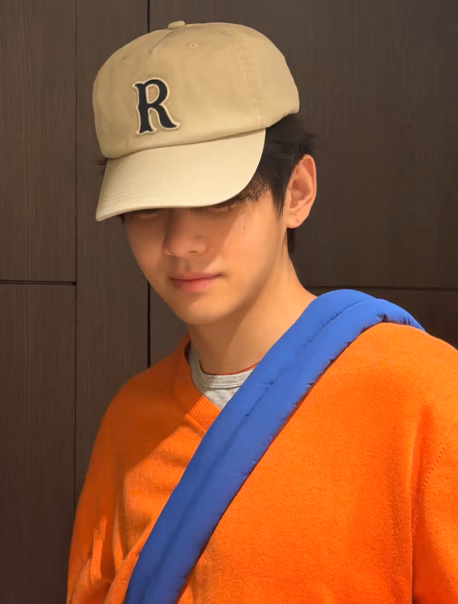 V creates color contrast with orange knitwear, a blue strap and a beige cap.