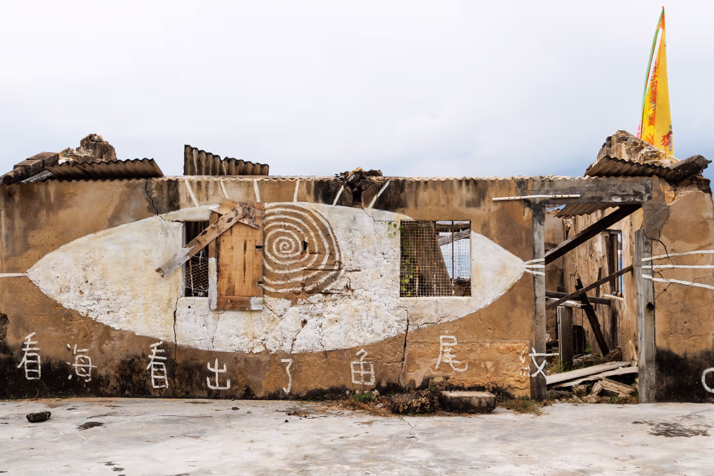 Damaged Kat O village-house exterior and an art installation