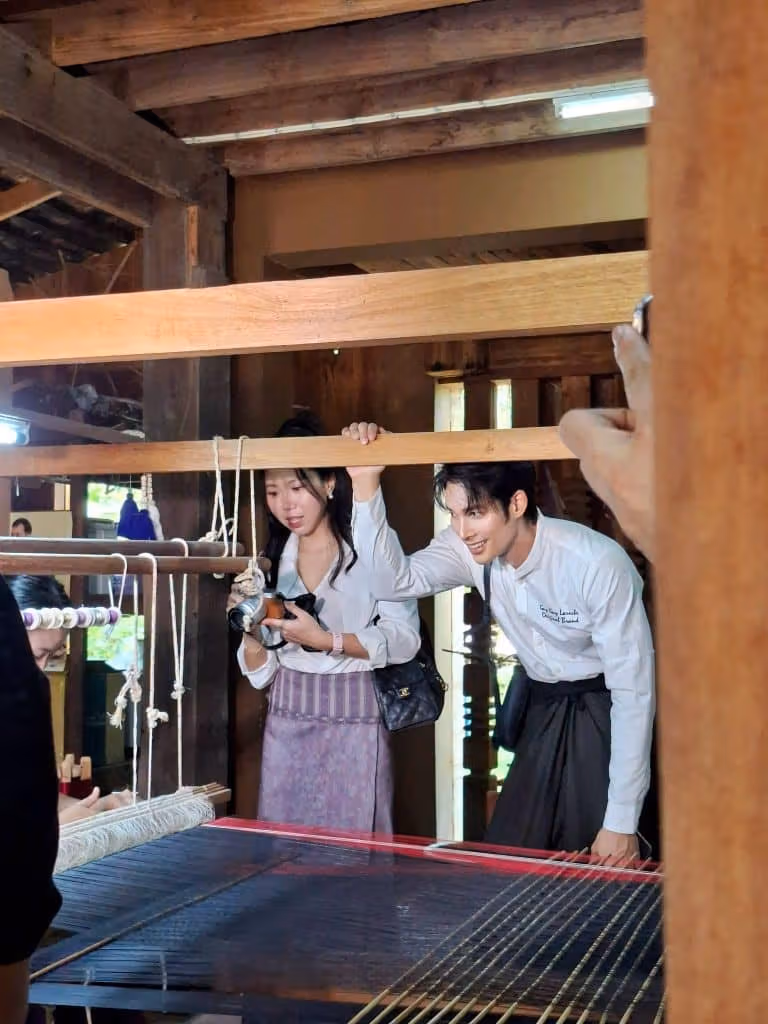 織機のそばで見る二人の見学者