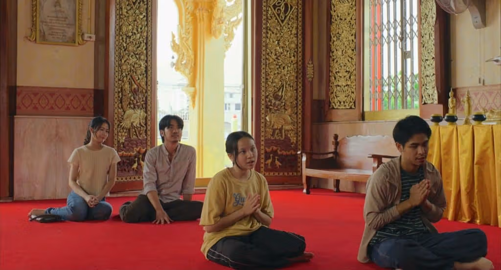 ภาพครอบครัวนั่งบนพื้นแดงในวัด