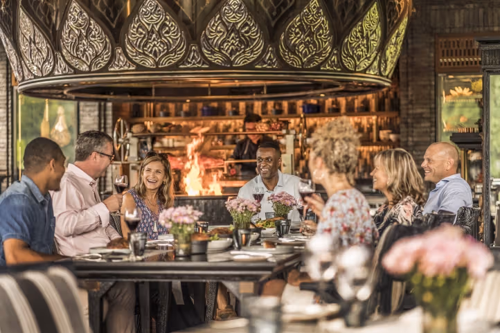 A group dining beneath woodcarving and a large lampshade