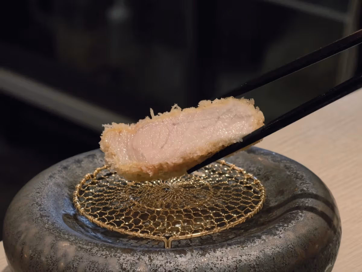 夹起的一片猪排展示切面与外层。