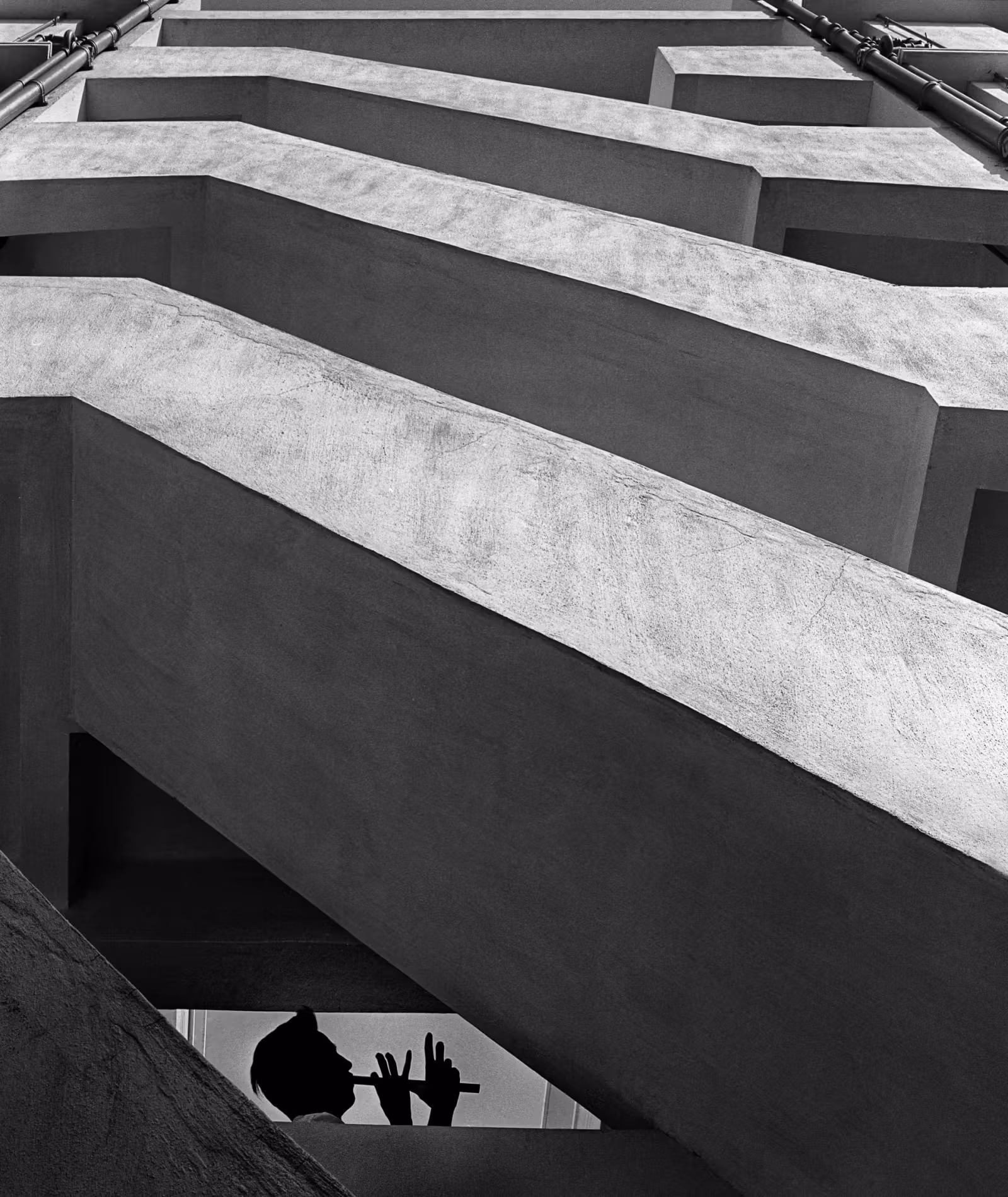 A silhouette playing an instrument beneath layered diagonal architectural structures