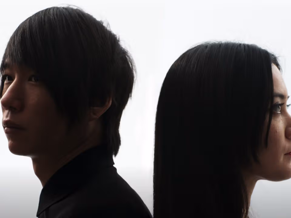 ภาพNONOTAKทางการมีคนสองคนยืนหันหลังพิงกันมองคนละด้านบนพื้นสว่าง