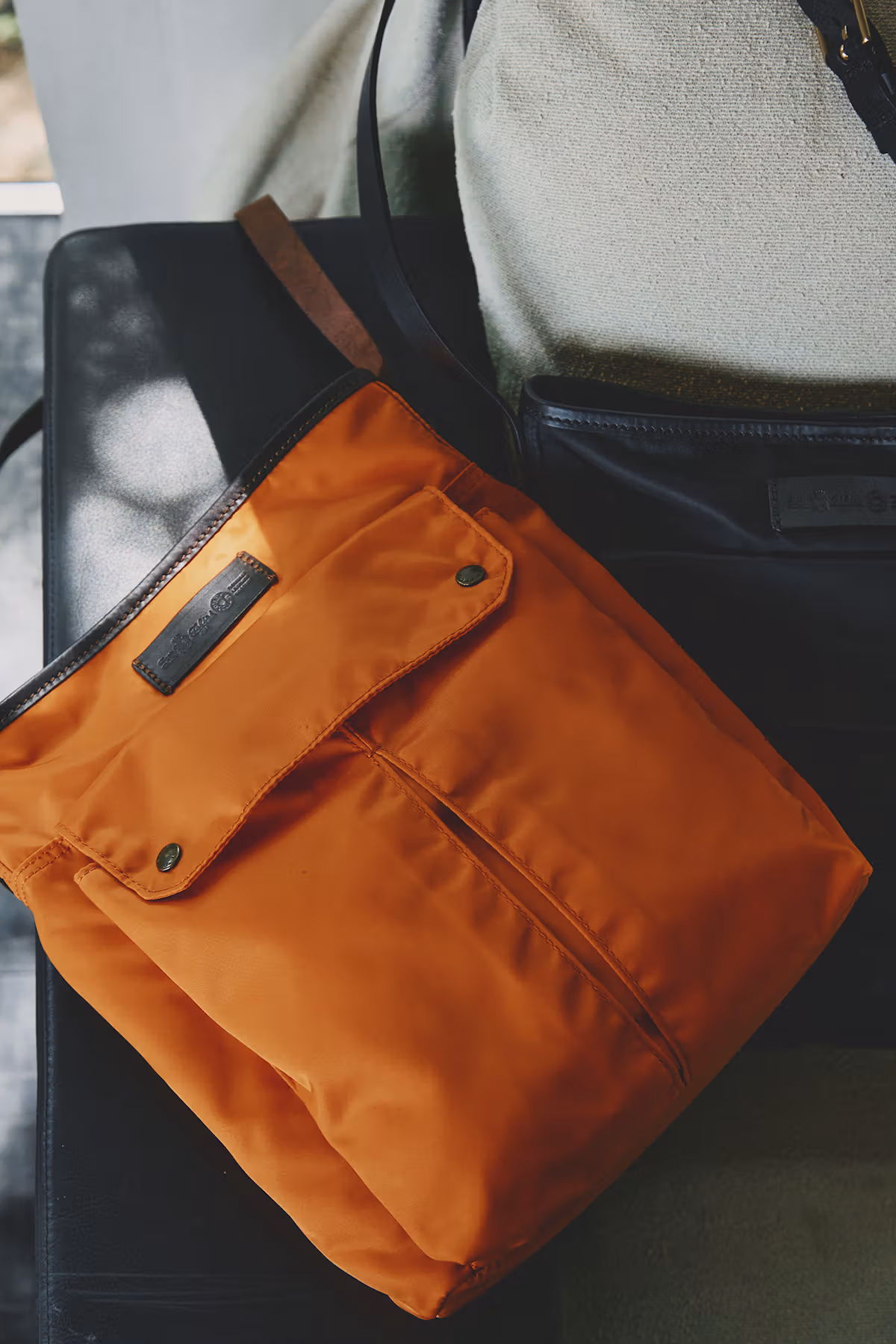 Orange nylon shoulder bag and dark straps