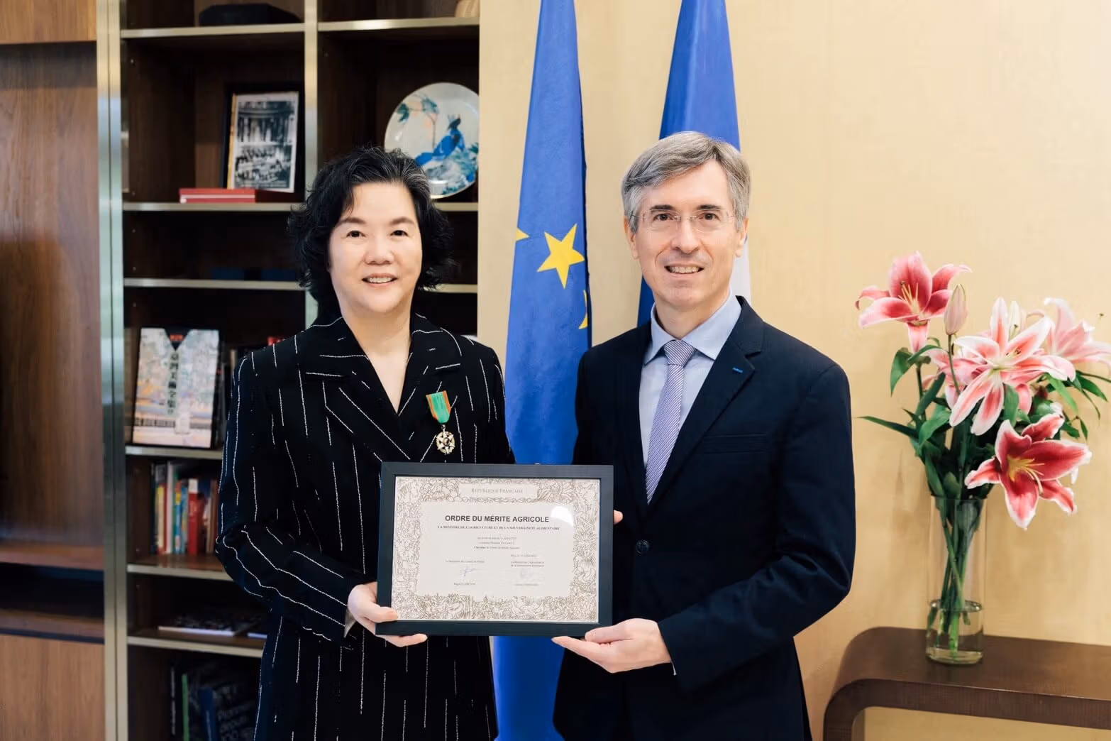 Justine Li wearing a medal and holding a certificate with Frédéric Laplanche