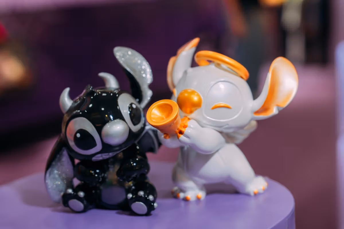 ฟิกเกอร์ Stitch นั่งสองตัวบนแท่นม่วง ด้านซ้ายสีดำมีเขา ด้านขวาสีอ่อนถือทรัมเป็ตส้ม