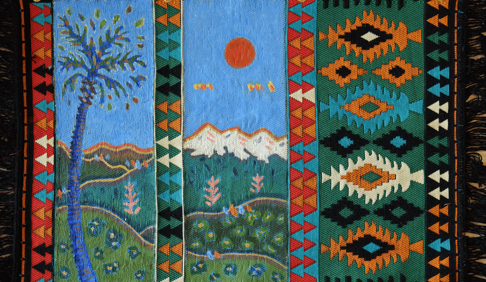 幾何学模様の織りラグに青空、赤い太陽、山や植物を描き、両側には多色の織り模様が残る