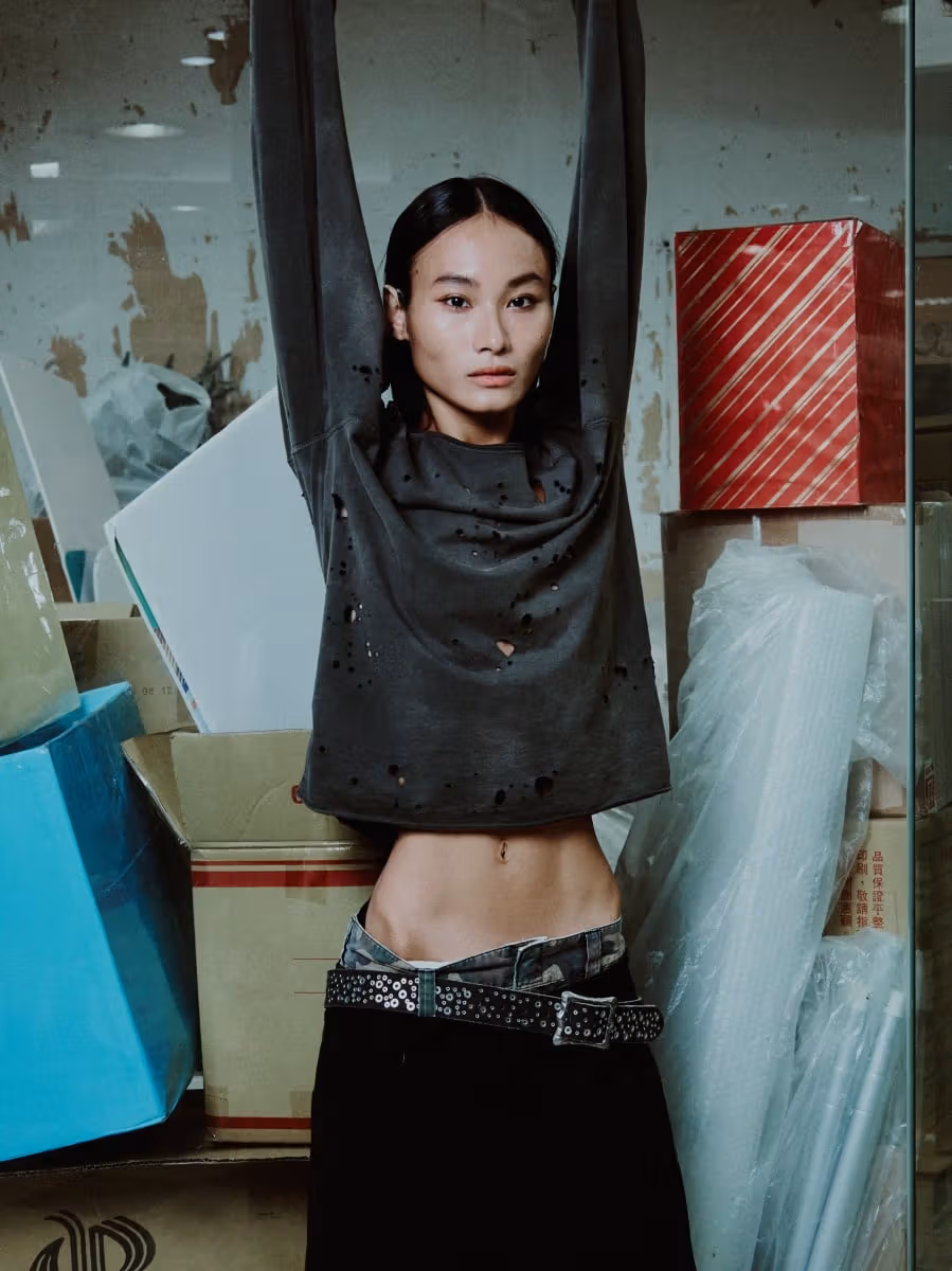 Model wearing a distressed black top and a metal-studded belt