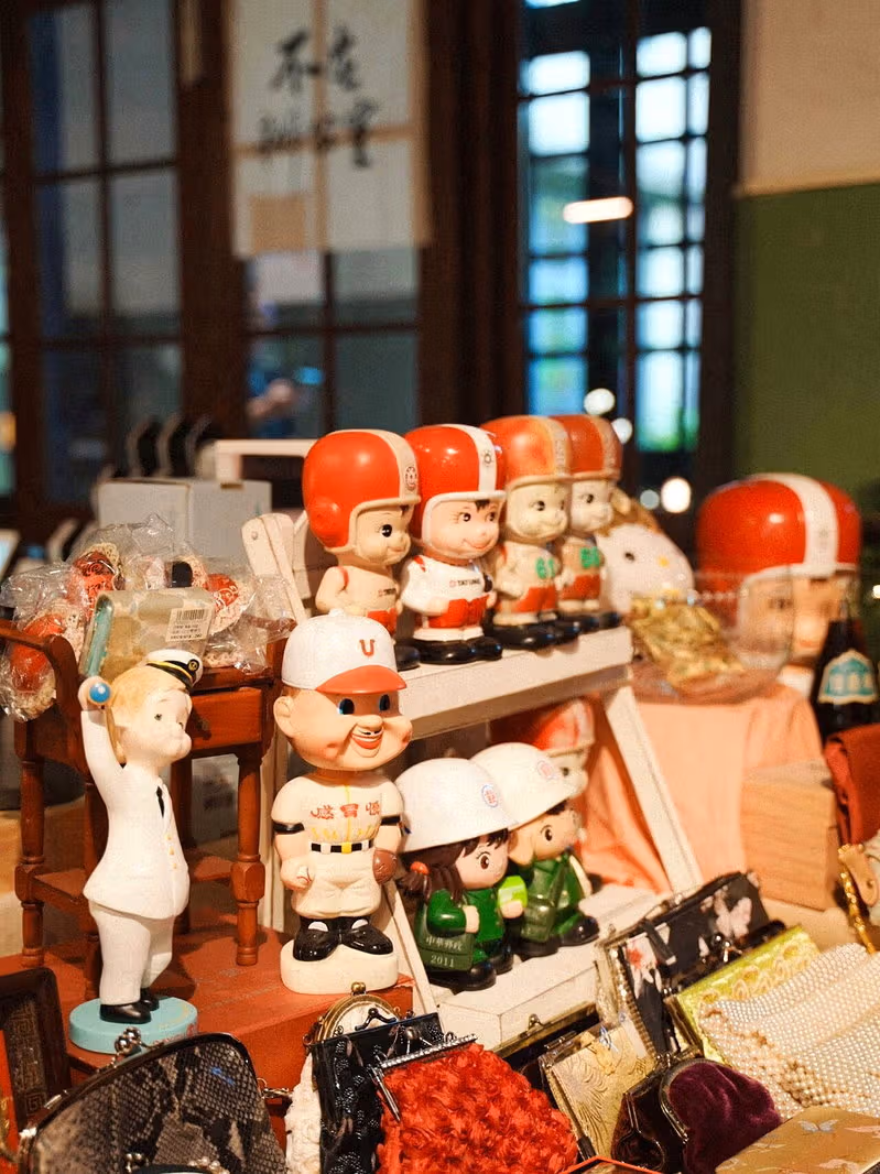 Red-capped baseball figurines and other small figures behind vintage bags