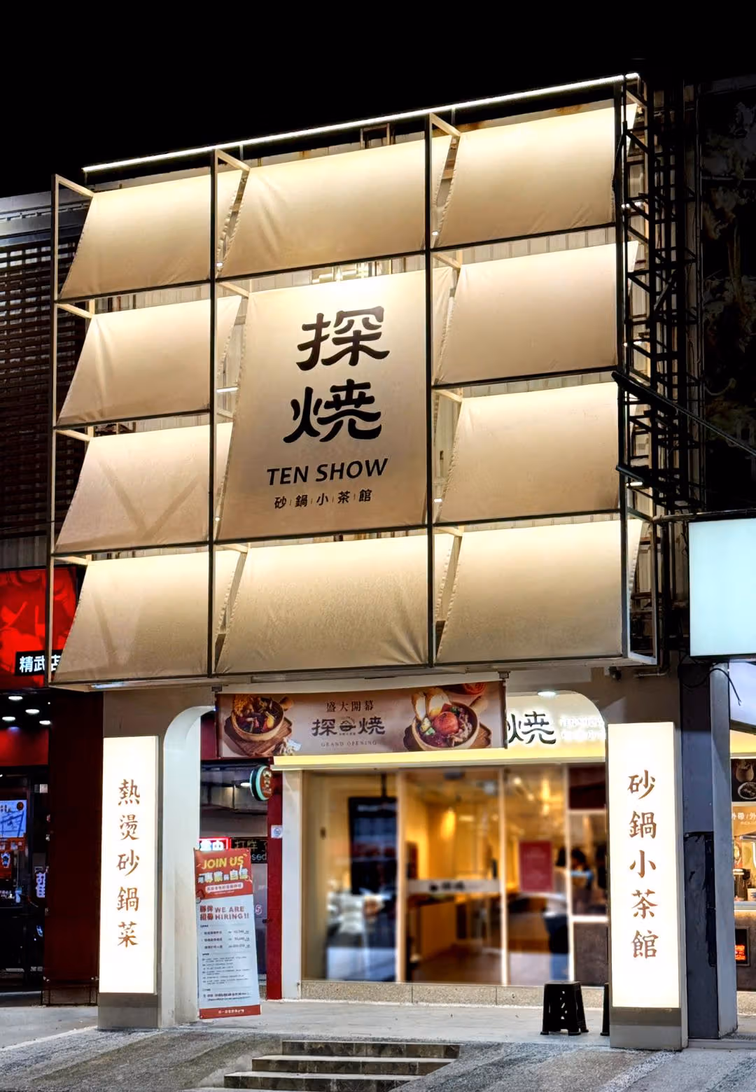 TEN SHOW facade at night with large pale panels and Chinese and English brand lettering
