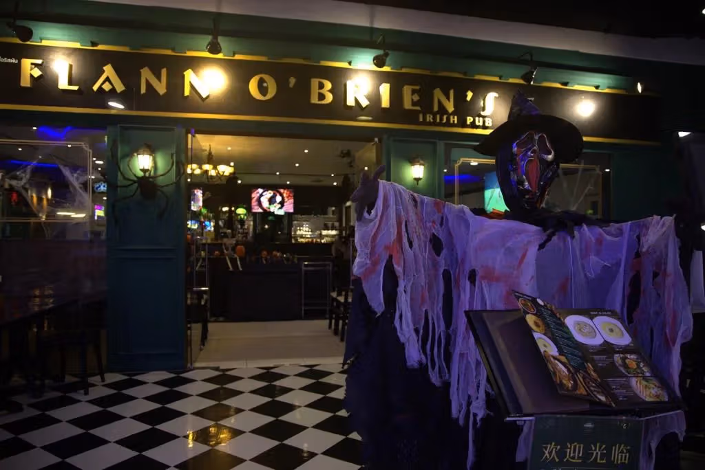 金色Flann O’Brien’s招牌下是绿色入口、黑白方格地板与穿破布装的恐怖布偶