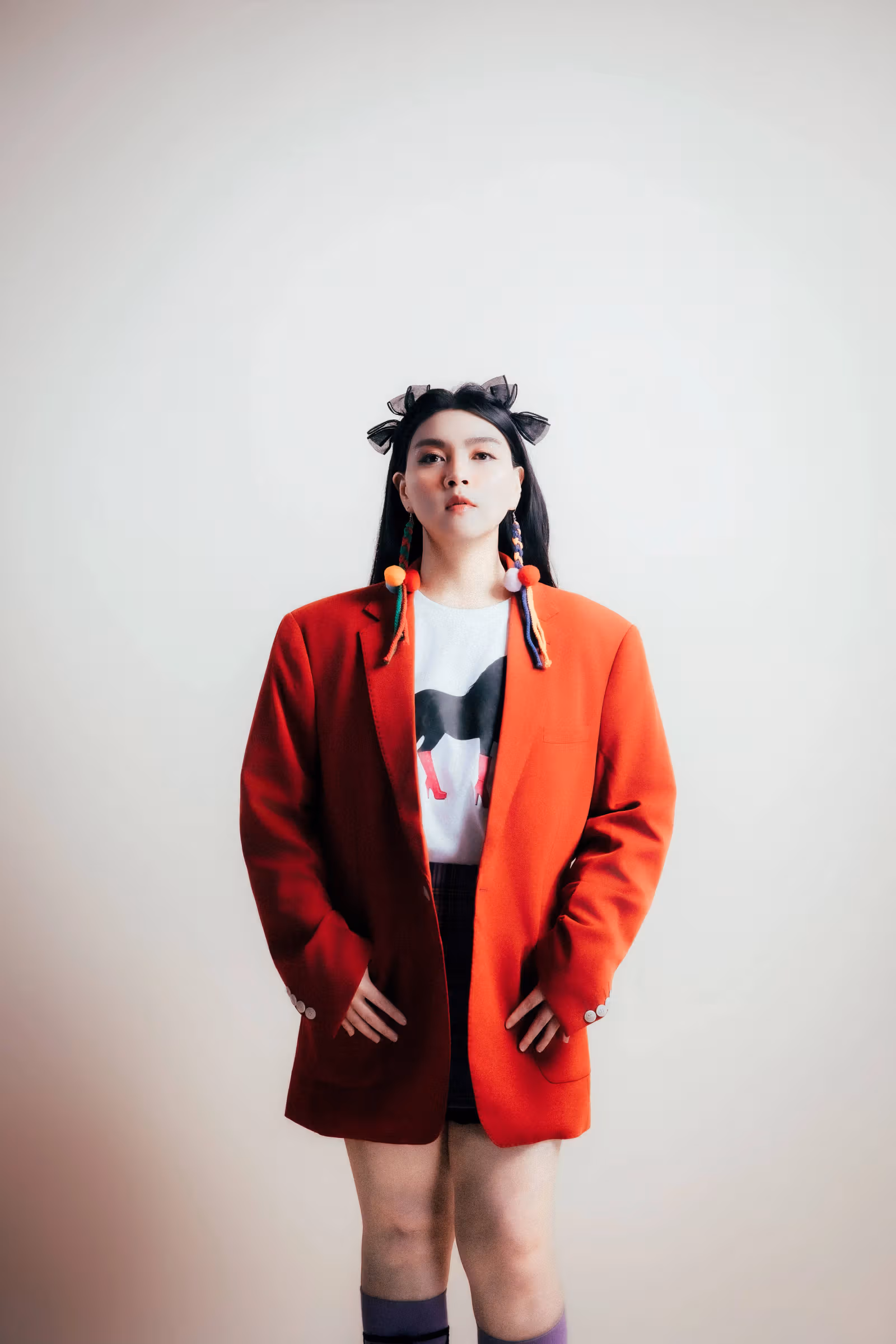 흰 배경에서 빨간 재킷과 그림 상의를 입고 카메라를 보는 라와