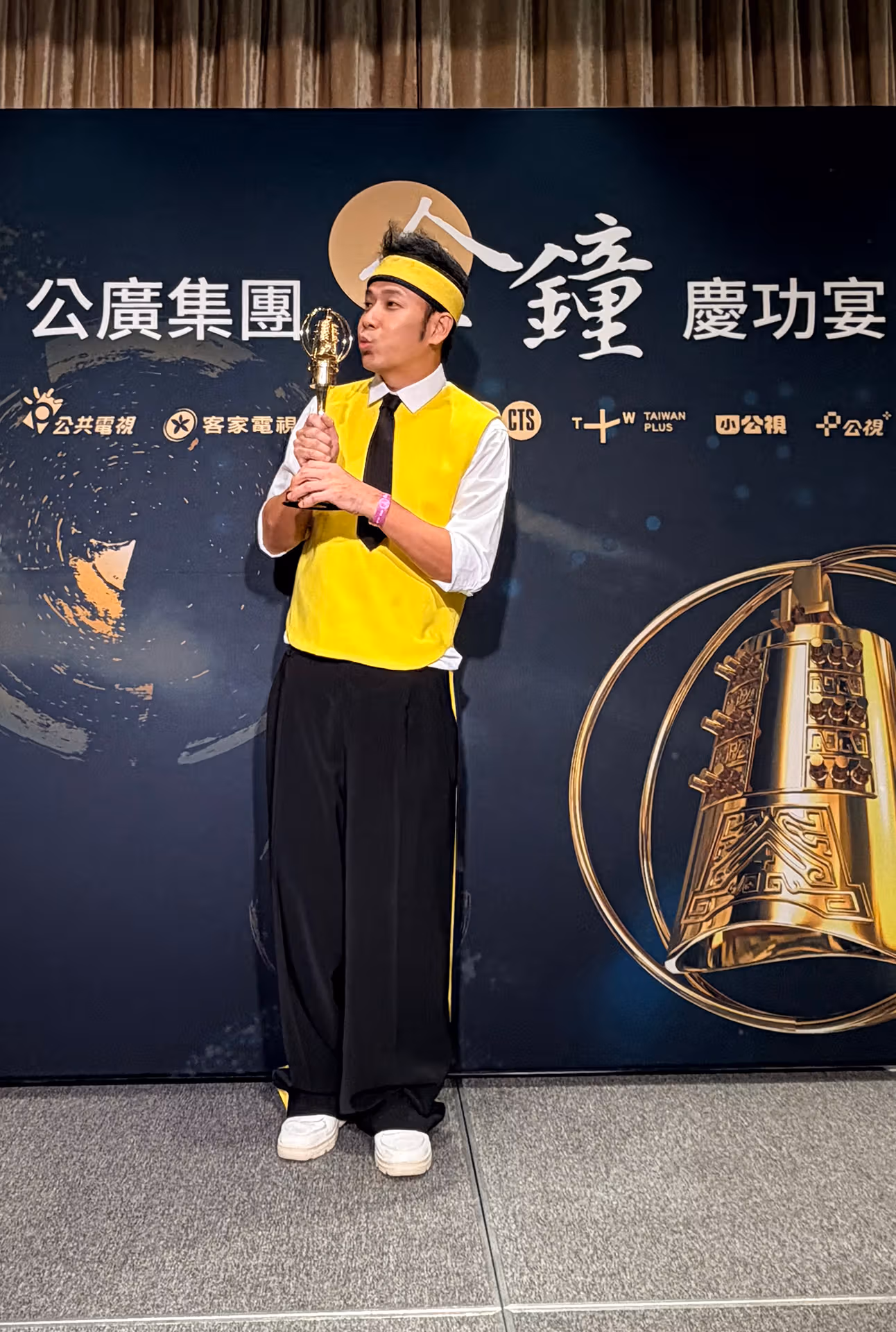 Banana Brother holds a gold trophy near his lips against a dark-blue-and-gold celebration backdrop