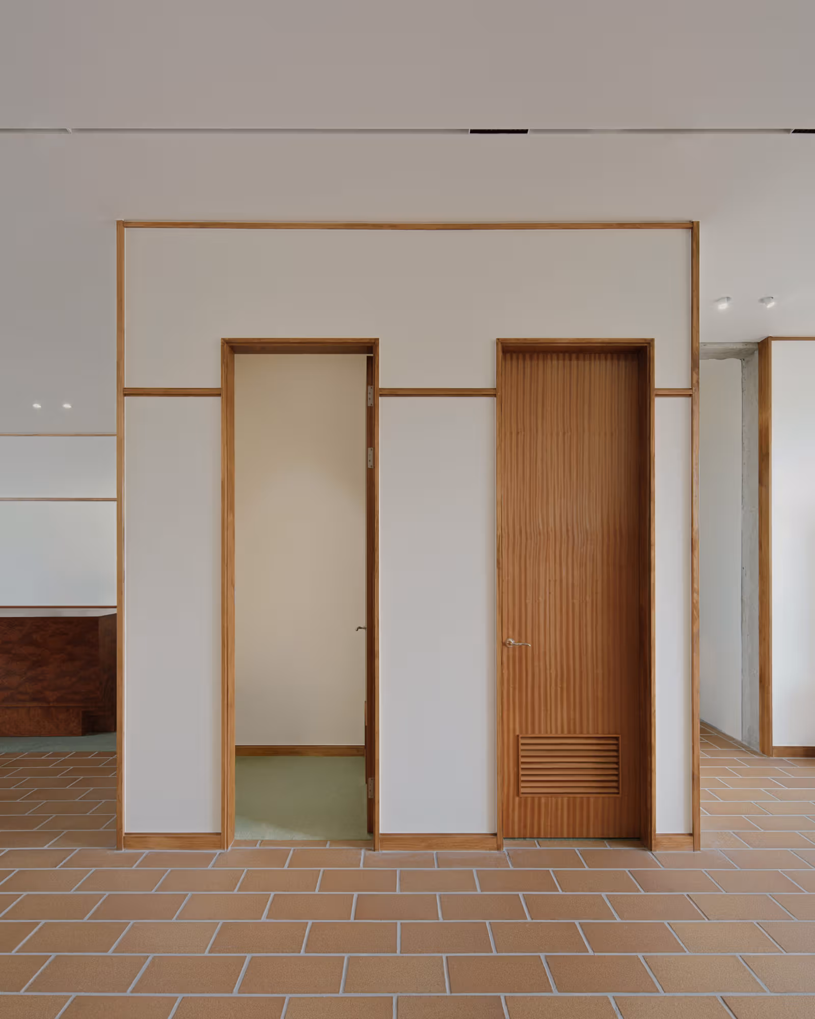 Layered wooden door frames, a vertically detailed door and pale walls