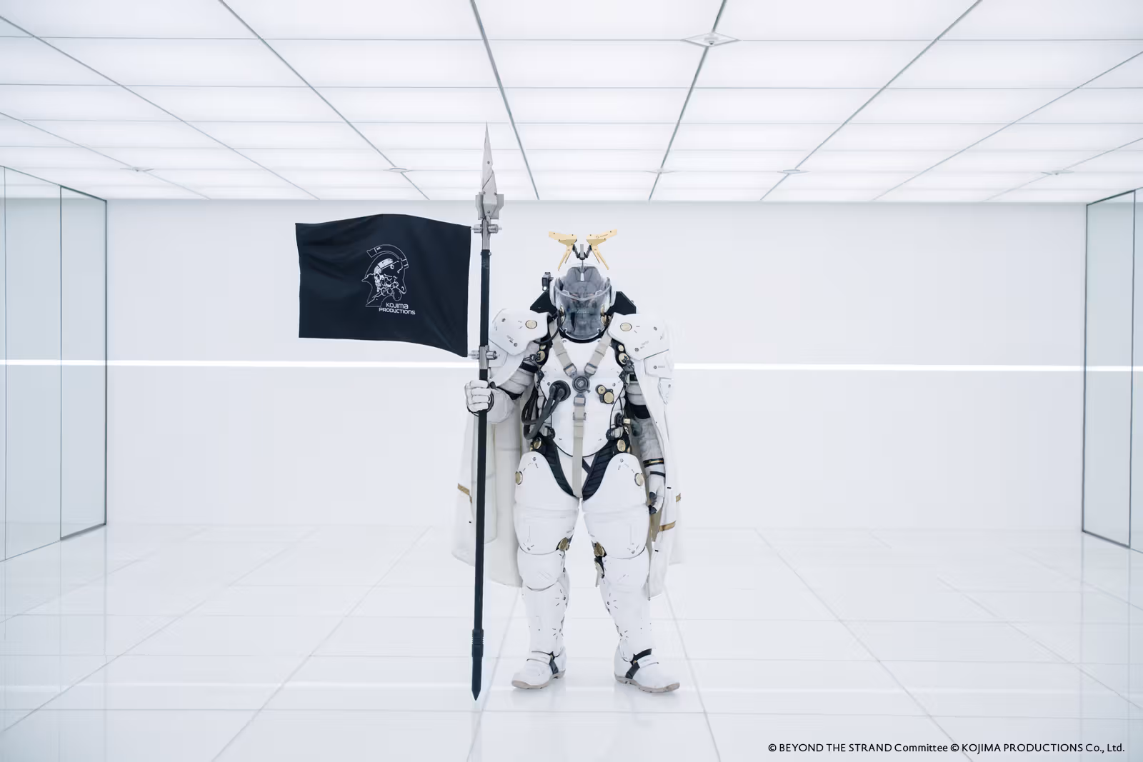 ภาพอ้างอิงทางการของ Ludens ถือธงยืนอยู่ในพื้นที่สีขาว