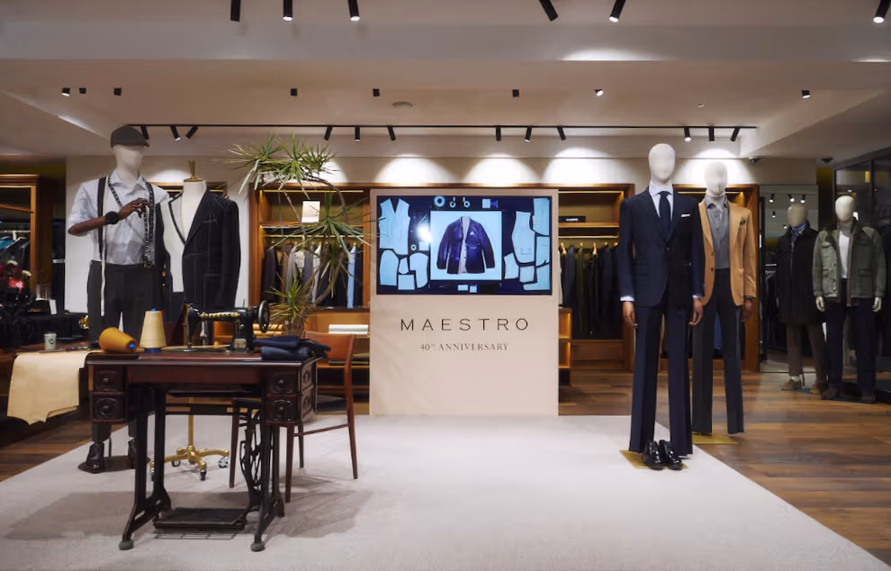 Maestro anniversary display with mannequins, suits, tailoring table and screen