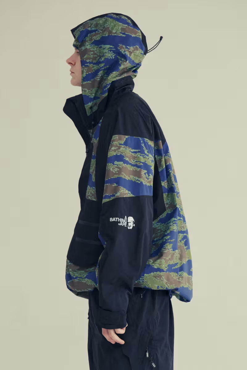Side view of a model in black and blue-green camouflage hooded outerwear