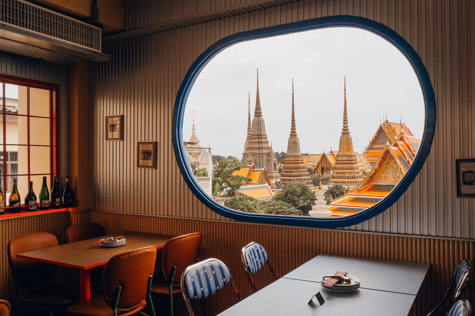 Mitr Street Bangkok frames Wat Pho through blue windows: red chicken, ThaiKi rooftop and booking deposits