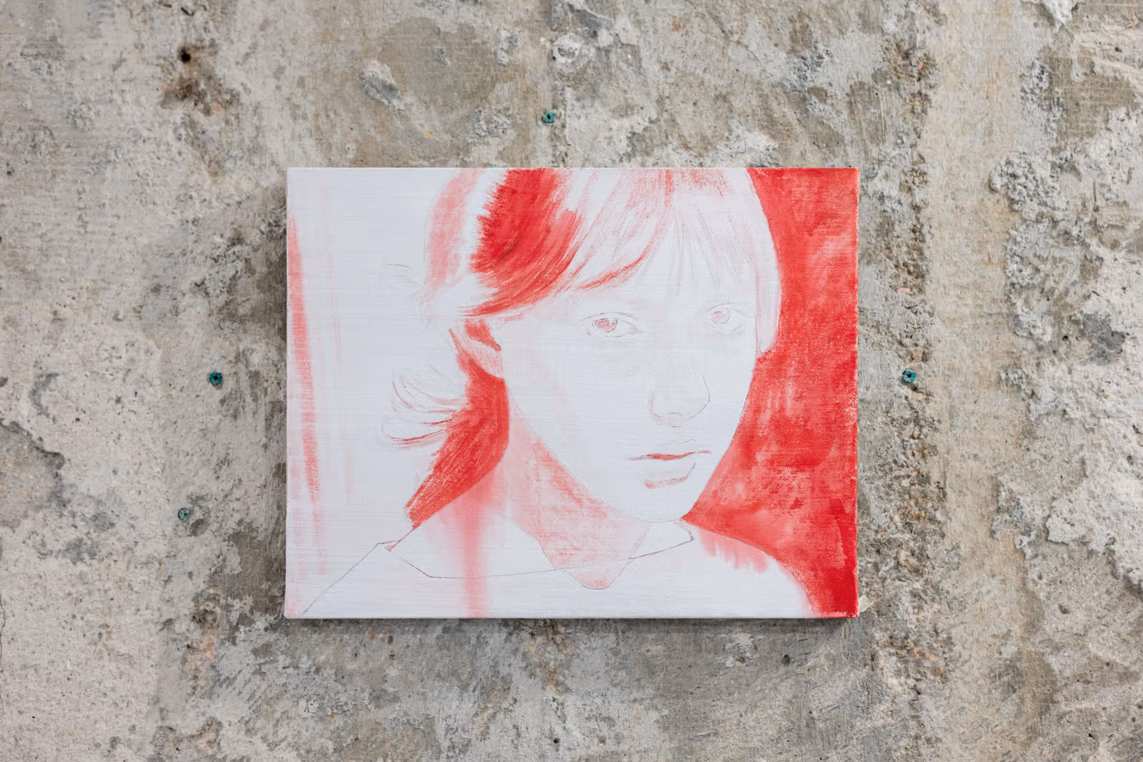 コンクリート壁に横長の小さな顔の絵が掛かり、淡い輪郭と赤い髪・背景の筆触が見える。