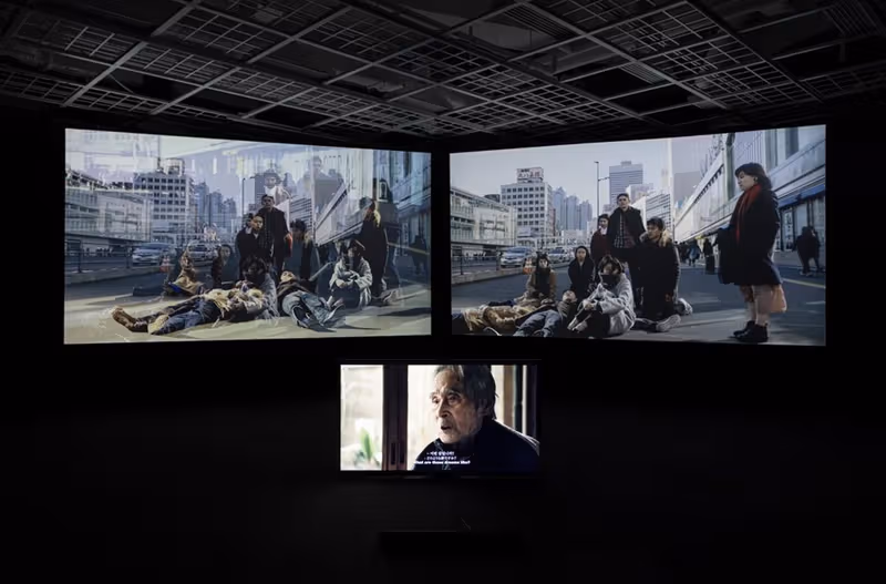 暗い展示室の3チャンネル映像とインタビュー画面