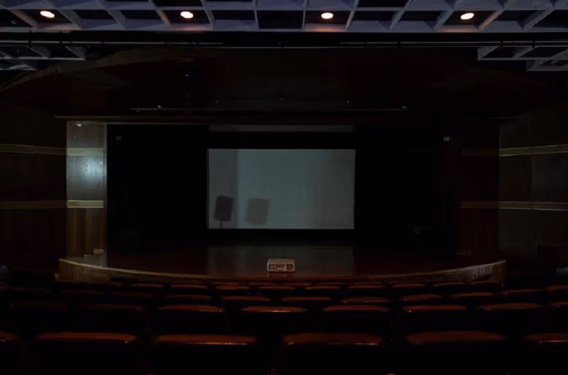 空白スクリーン前に椅子が並ぶArt Sonje地下Art Hall