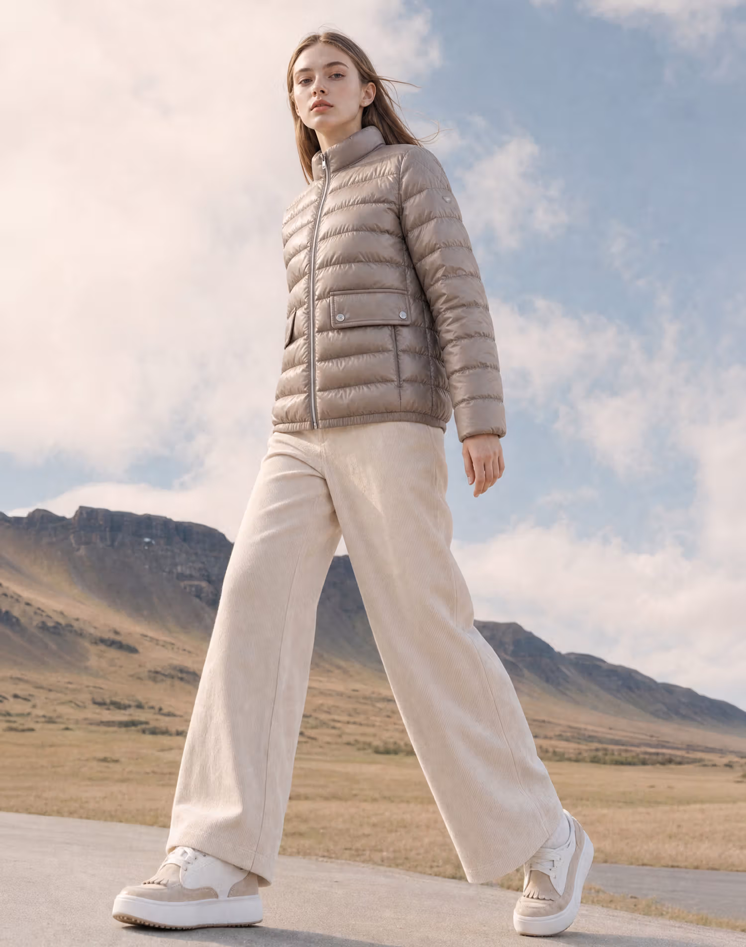 Woman in a short beige down jacket, pale wide trousers and white shoes