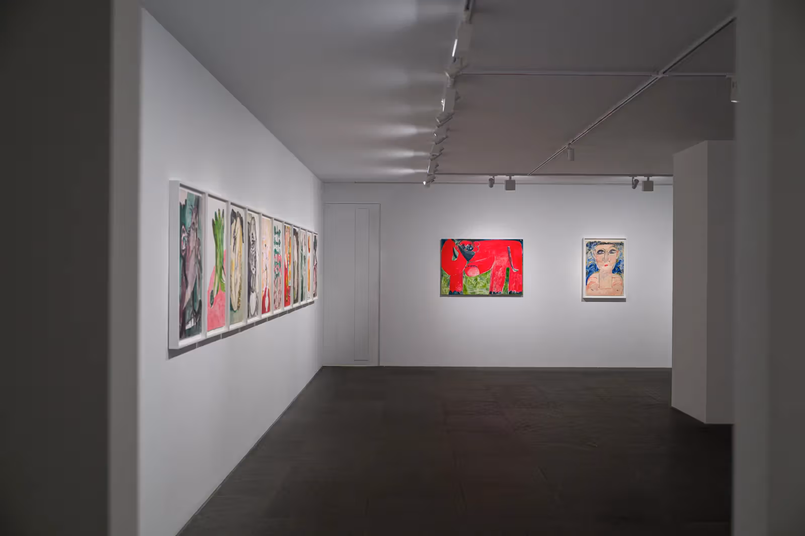 從入口方向看《日日耕》展場，左側為成排小畫，端牆有紅色動物及人物畫。