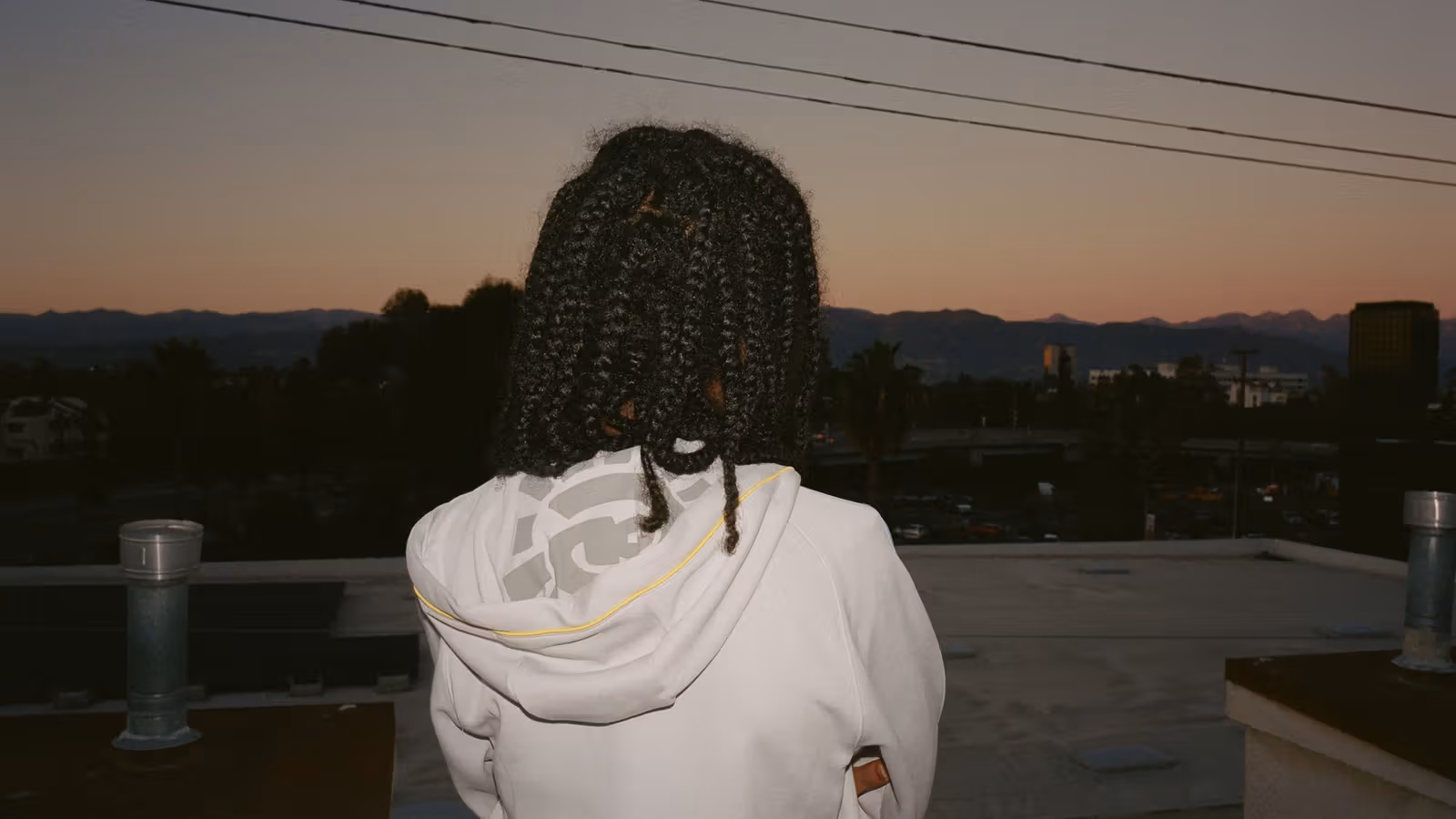 Brand styling photograph of the grey hooded top from behind.