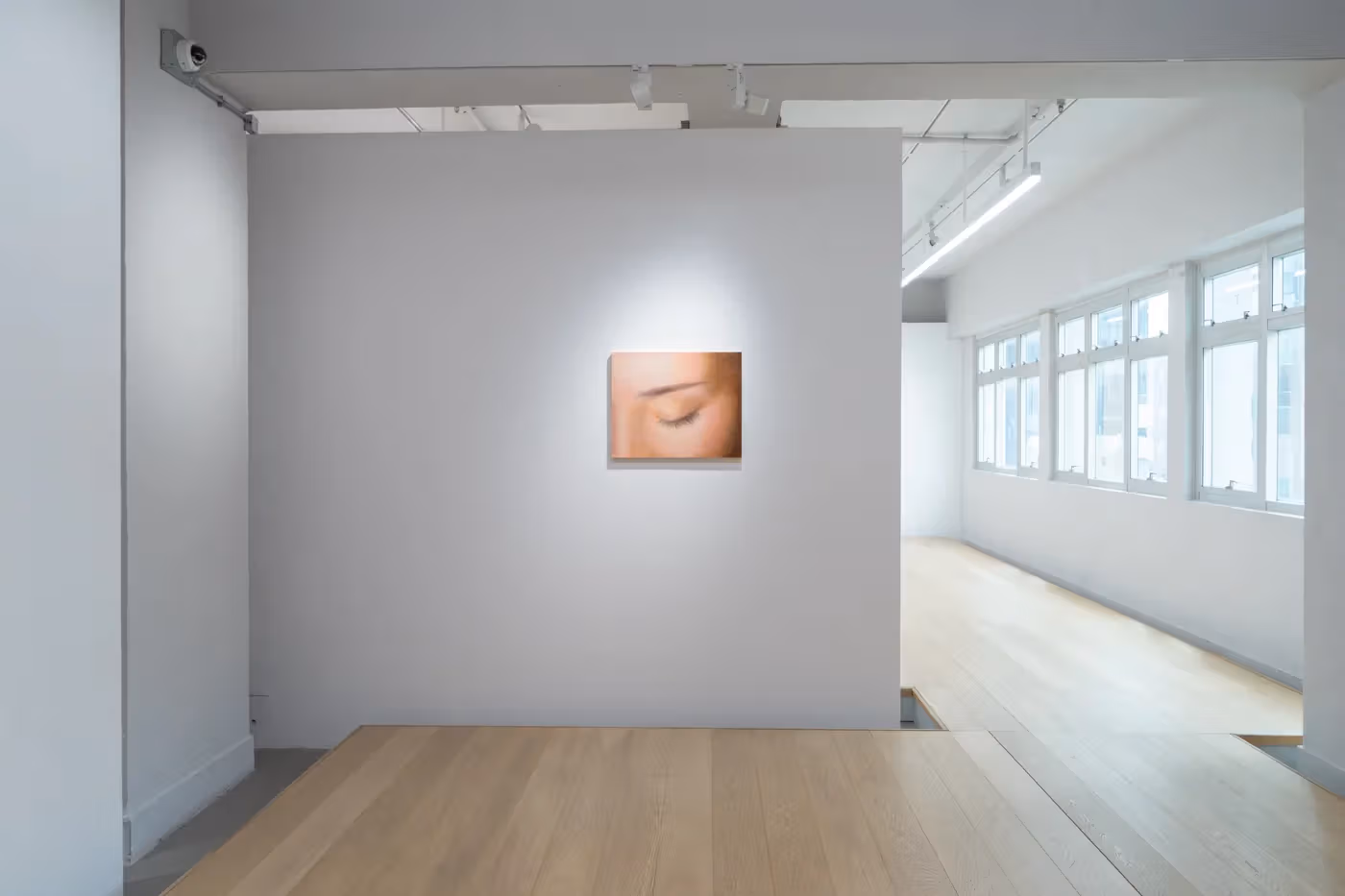 A closed-eye image on a corner wall contrasts with the windows and passage beside it.