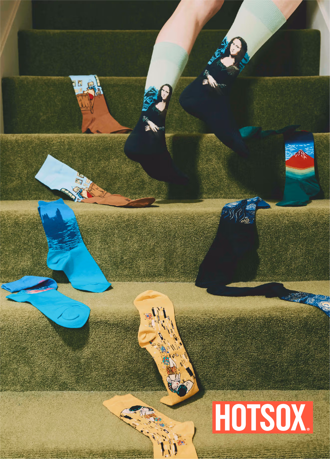 A model wears Mona Lisa socks above steps holding Fuji and other artwork-patterned socks