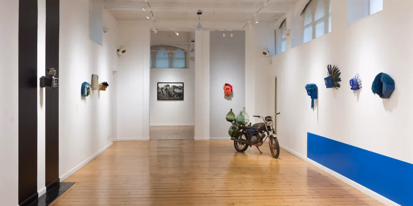 White gallery with wall masks and a central motorcycle display
